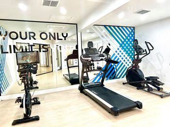 a gym with several exercise machines and a sign that says your only limit is cardio